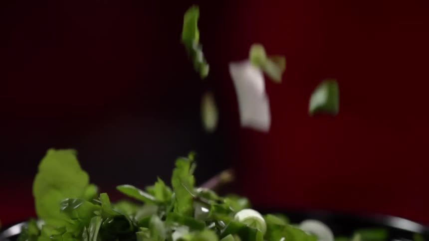 Greens are being dropped on a salad