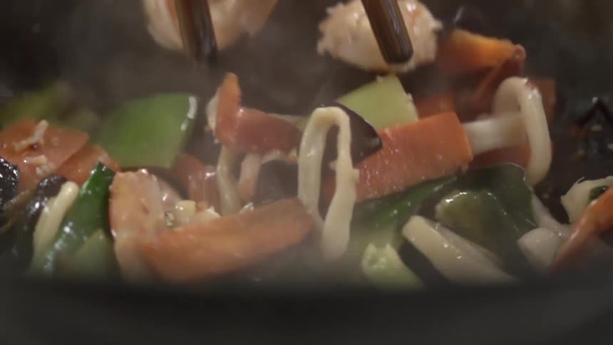 Tongs stirring an asian cuisine in a pan
