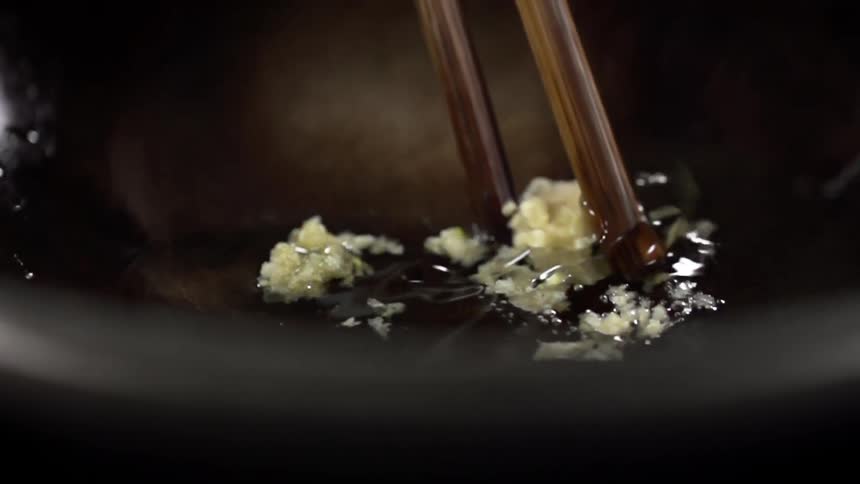 Food is mixed around in the oil on the pan