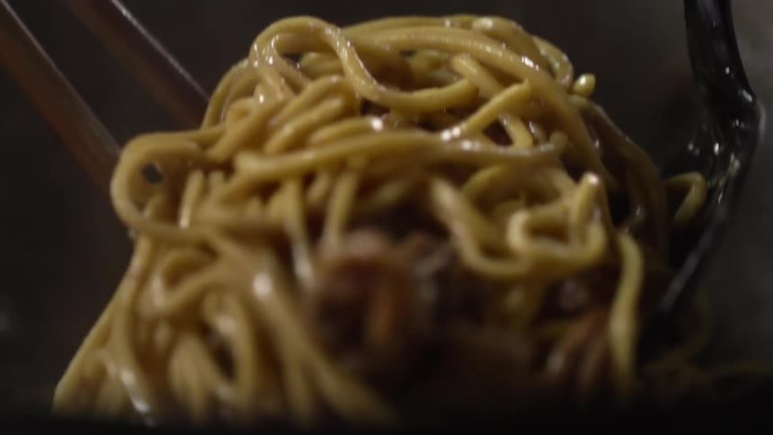 A fork and tongs pick up a small pile of spaghetti and pieces of meat