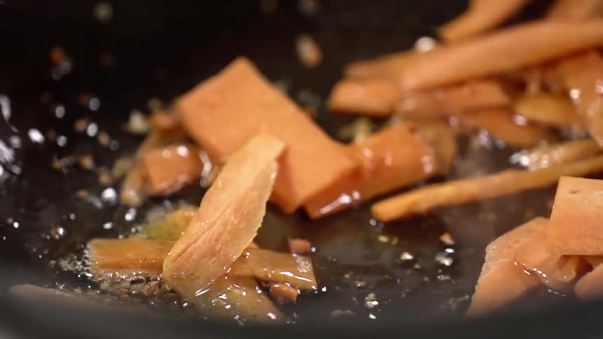 Vegetables are sauteed and stirred with chopsticks in a pan with oil