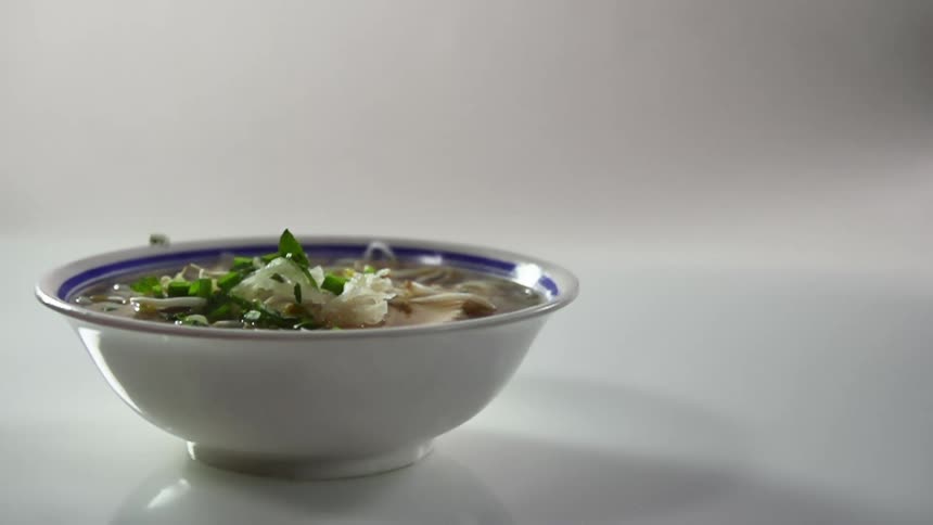 Garnish is being dropped on the bowl of soup