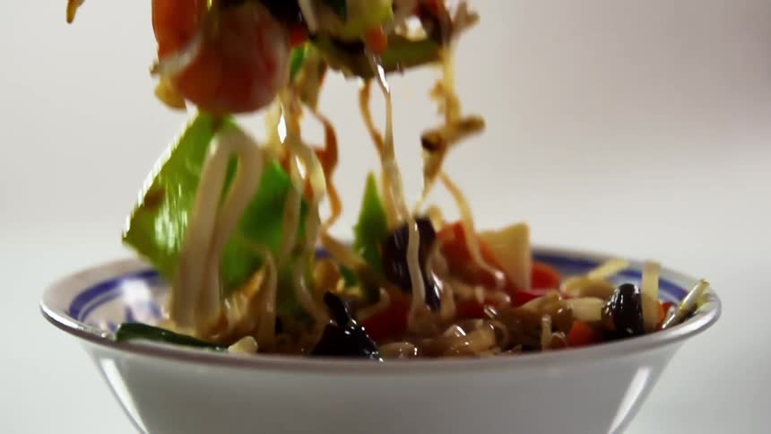 Noodles with vegetables and shrimp served in a ceramic bowl