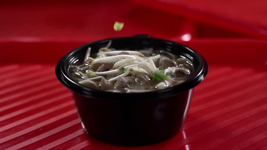 Chives falling on a bowl of food set up for a photo shoot