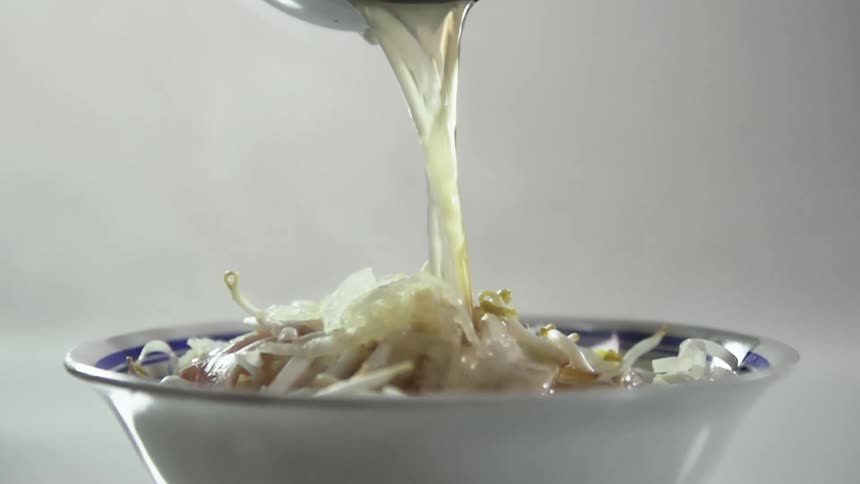 A bowl with sprouts and vegetables with sauce being poured onto it