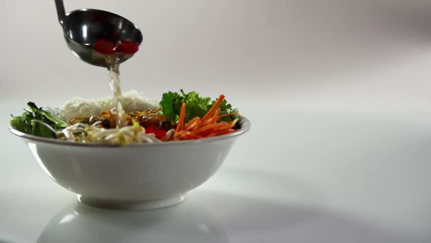 Silver ladle pours topping onto a vegetable salad