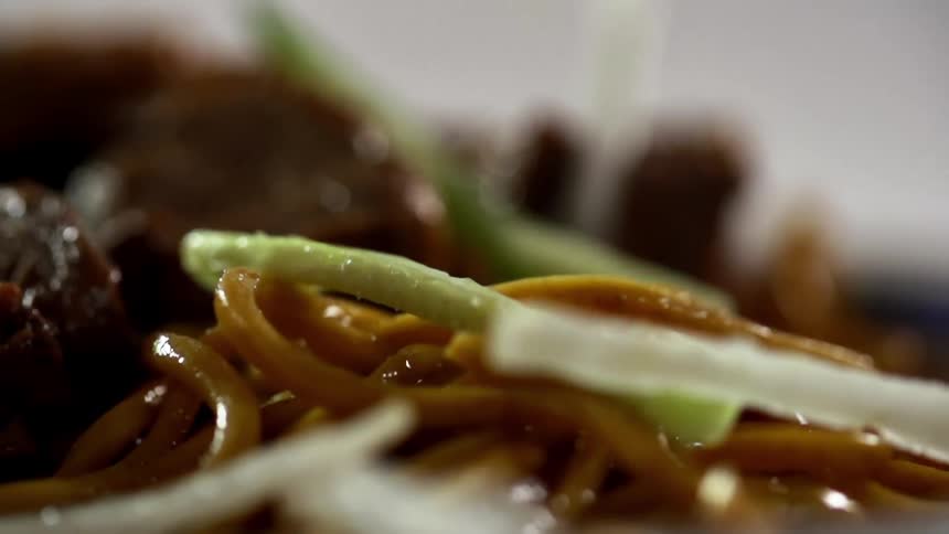 Sliced vegetables fall over noodles with meat