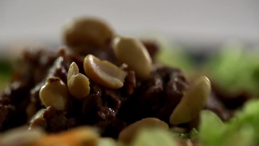 Peanuts are dropped down to garnish plated food