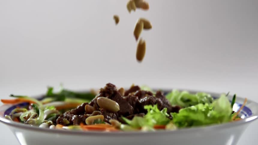 Peanuts dropping on to a bowl of food