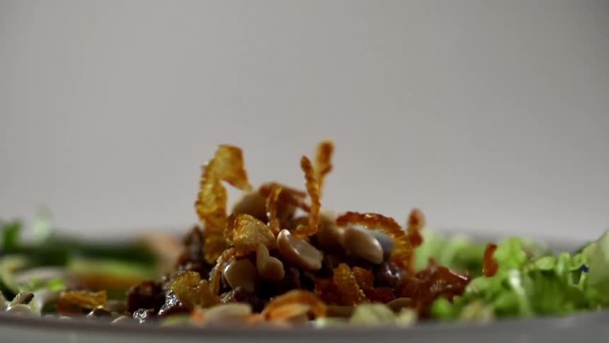 Garnishes being dropped on a salad for a photo shoot