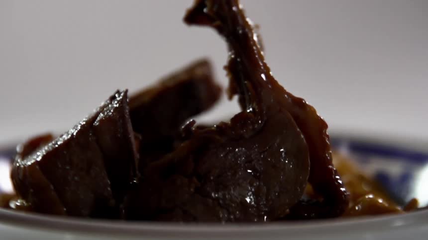 Slices of marinated beef are dropped onto a bowl of stir fried noodles