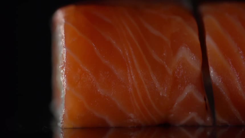 Cook cuts salmon in half for sushi