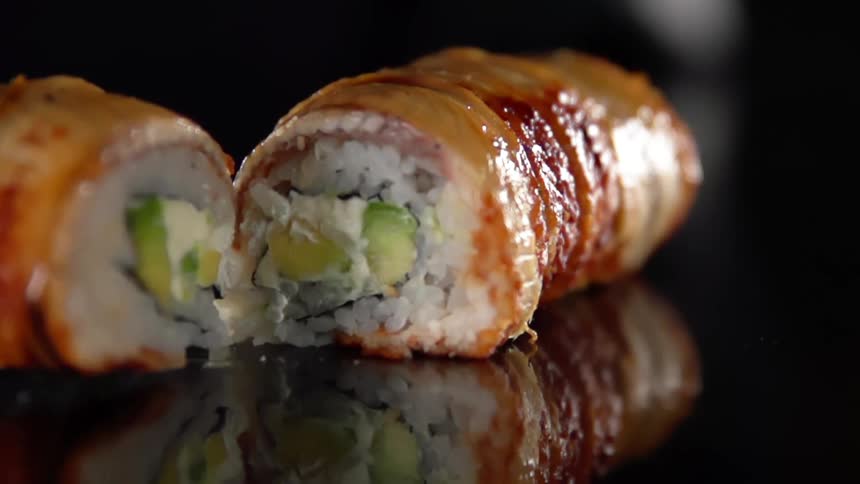 Sushi roll cut in half over a reflective surface