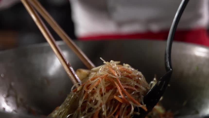 A person lifts food out of a wok