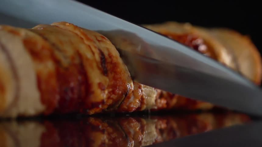 A sushi roll is carefully cut in half with a very sharp chefs knife