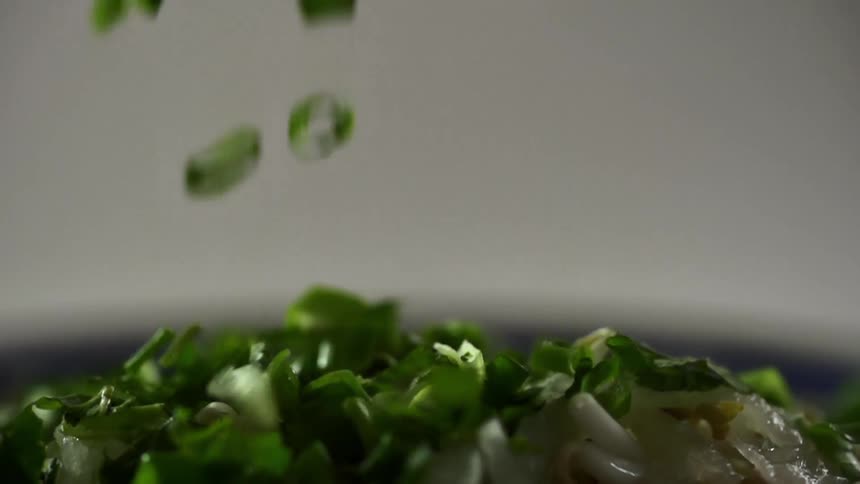 Sliced green onion is dropped and forms a pile
