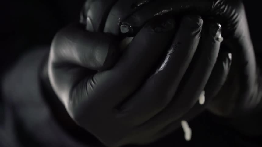 Male wearing black latex gloves place their hands around a ball of white sticky rice and applies pressure to hold the ball together