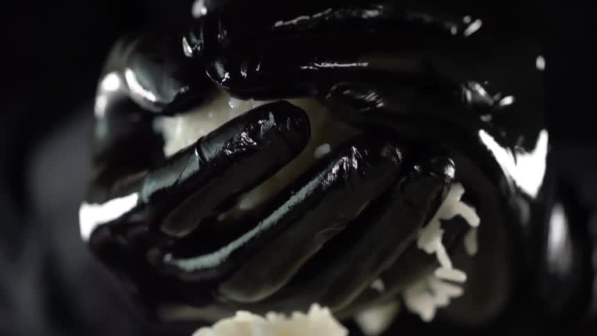 A person with black gloves balling up rice