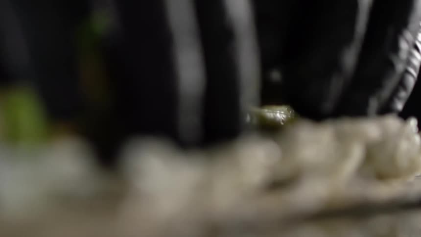 A person cooking puts avocado on top of rice