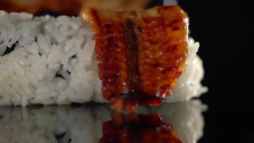 A person with black gloves placing bacon on rice