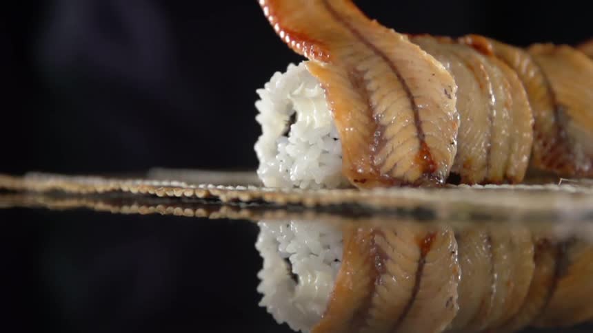 A person puts fish on top of sushi