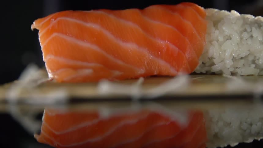 A person cooking sushi puts fish on top of rice