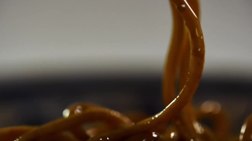 Noodles covered in sauce descending into a pile