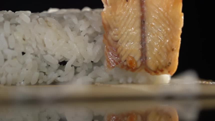 Fish being wrapped onto rice to make sushi
