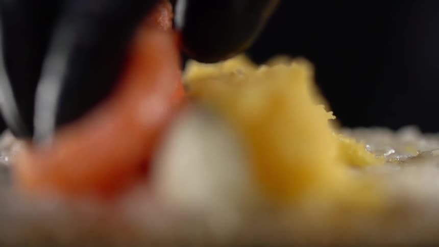 A person places a piece of fish on top of rice