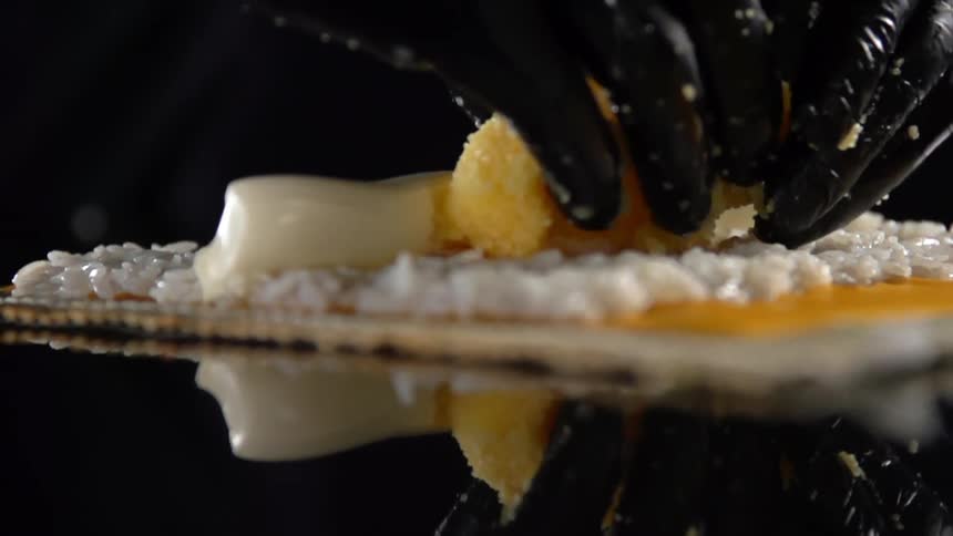 Black gloved hands place food on a placemat