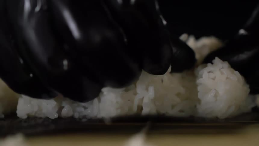 A person wearing black disposable gloves is handling a pile of white rice