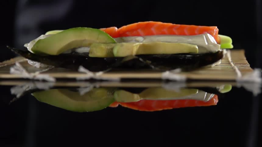 A person puts slices of avocado on food