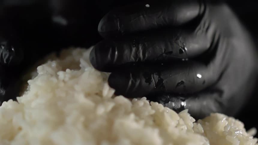 Cook with black gloves takes by handfuls of boiled rice