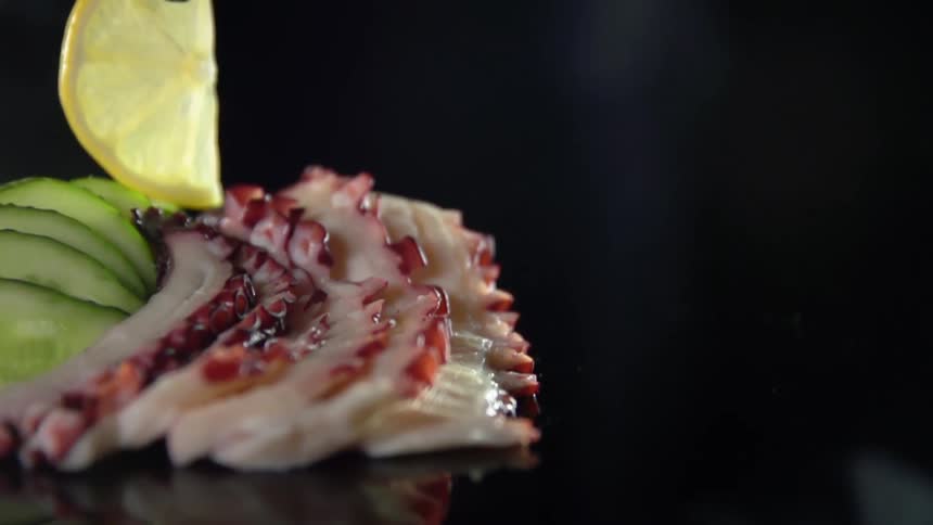 A person places a lemon slice on food for a photo shoot