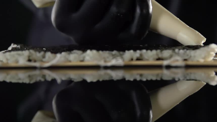 A person is putting cream on sushi
