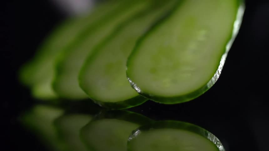 A person places slices of cucumber down for a photo shoot