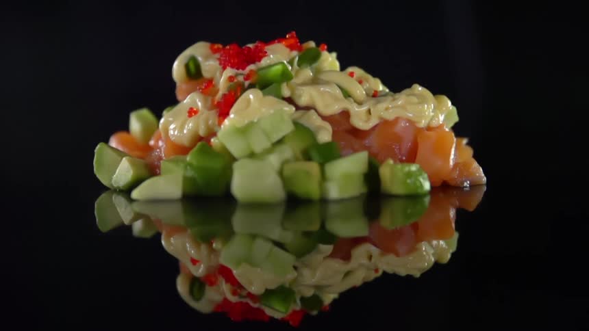Roe being dropped onto a pile of vegetables covered in a pale yellow sauce