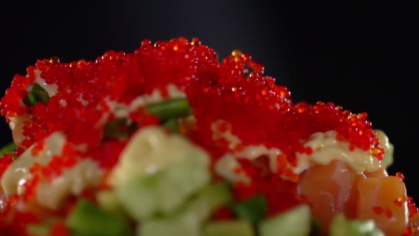 Red caviar is dropped onto the top of a layer of creamy sauce covering an entree made with tomato