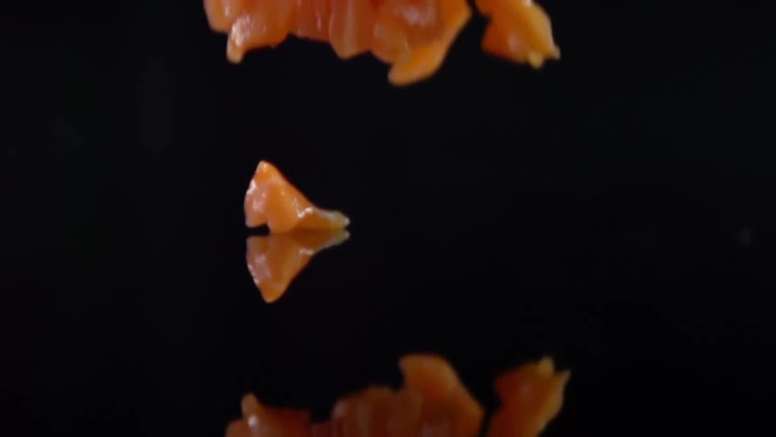 Close up pieces of raw chicken dropping on reflective countertop surface