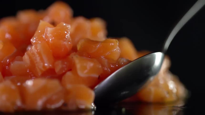 Finely chopped raw salmon meat picked up with a metal spoon