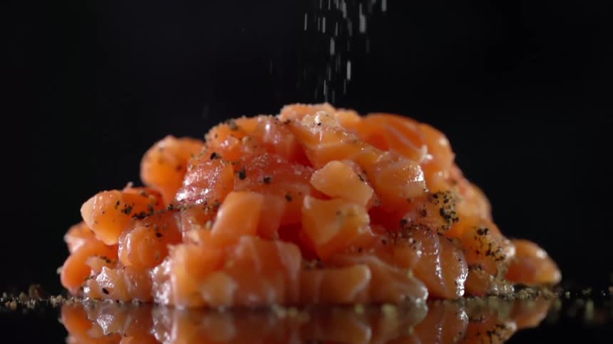 Salt being poured on a stack of cubed uncooked meat