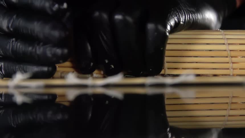 Black gloved hands grasp a bundle of wooden skewers