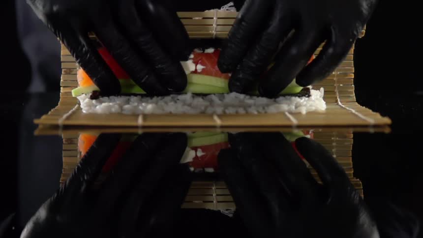 A person is rolling some sushi on a mat