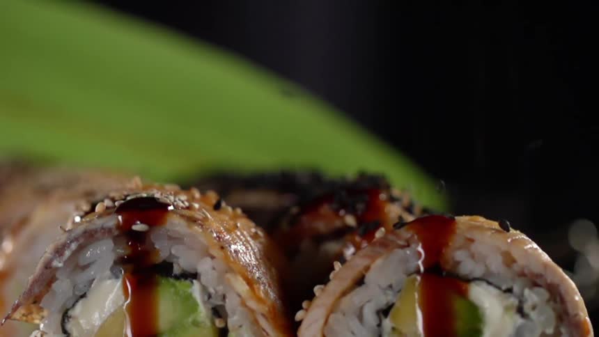 Sesame seeds falling in slow motion onto sushi rolls
