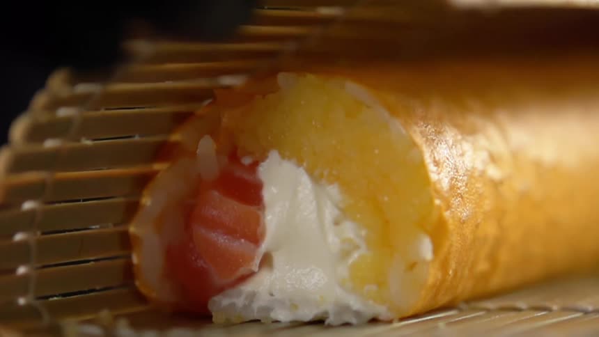 Cook with black gloves rolls sushi with bamboo mat in studio