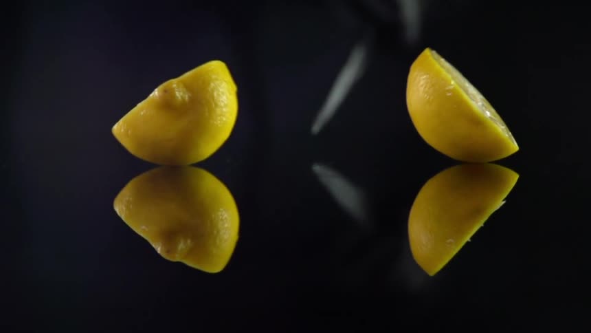 Man with black gloves cuts a lemon in half in studio