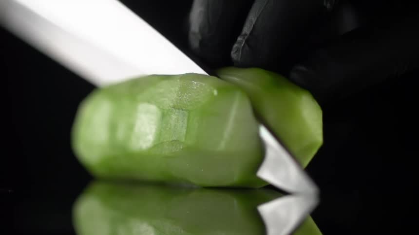 Chef wearing black latex gloves cuts vegetables with a sharp kitchen knife