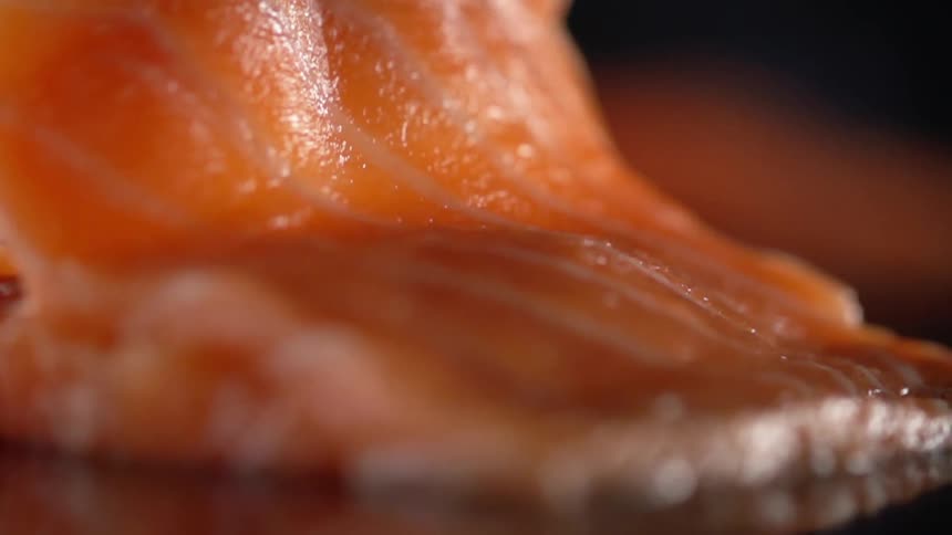 A piece of salmon being picked up with tongs