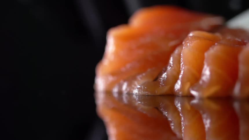 Close up of a cook cutting salmon with a knife for sushi in studio