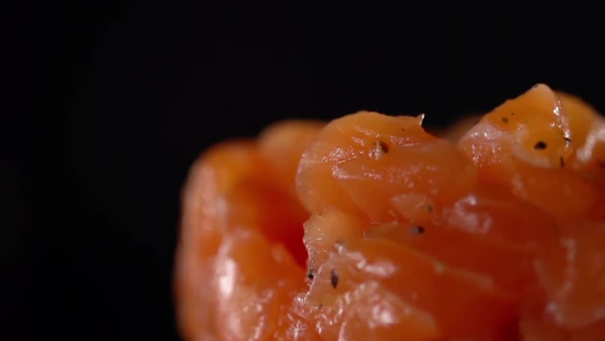 Appetizing raw fish with a few flakes of black pepper sits in a pile